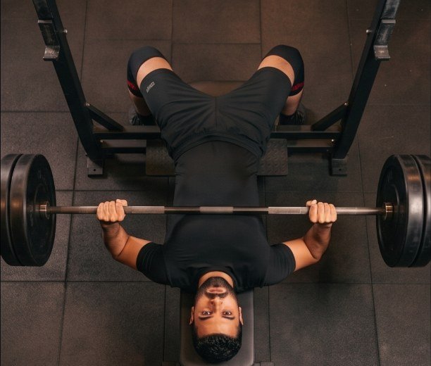 Bench press bottom position from directly overhead, the frame where elbow flare is visible