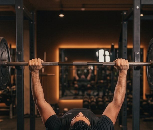 Bench press setup seen from behind the head: wide grip established on the racked bar with arms extended and head resting on the bench